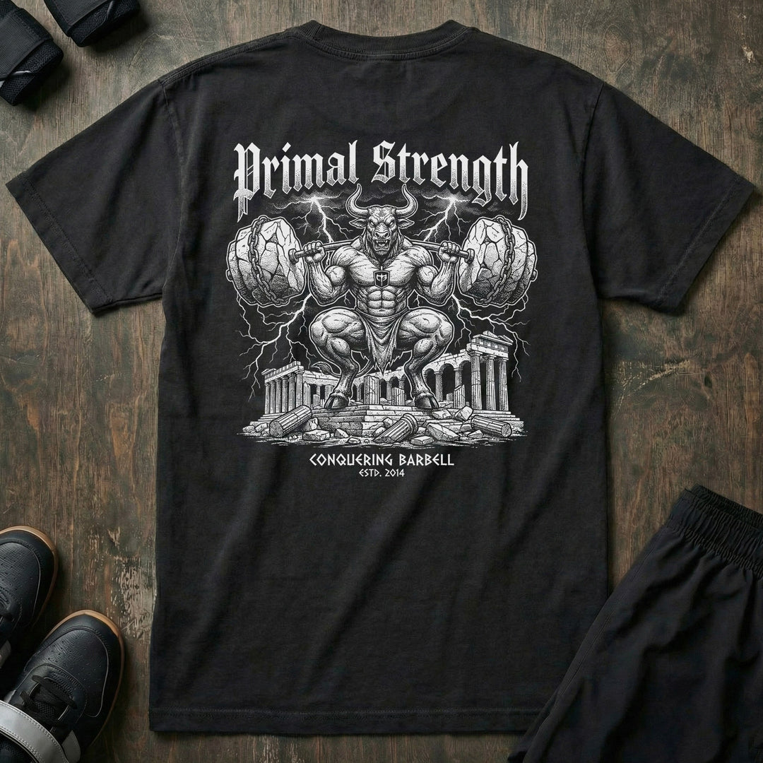 Primal Strength Minotaur relaxed fit tee in Black: a massive minotaur squatting a barbell loaded with boulder plates