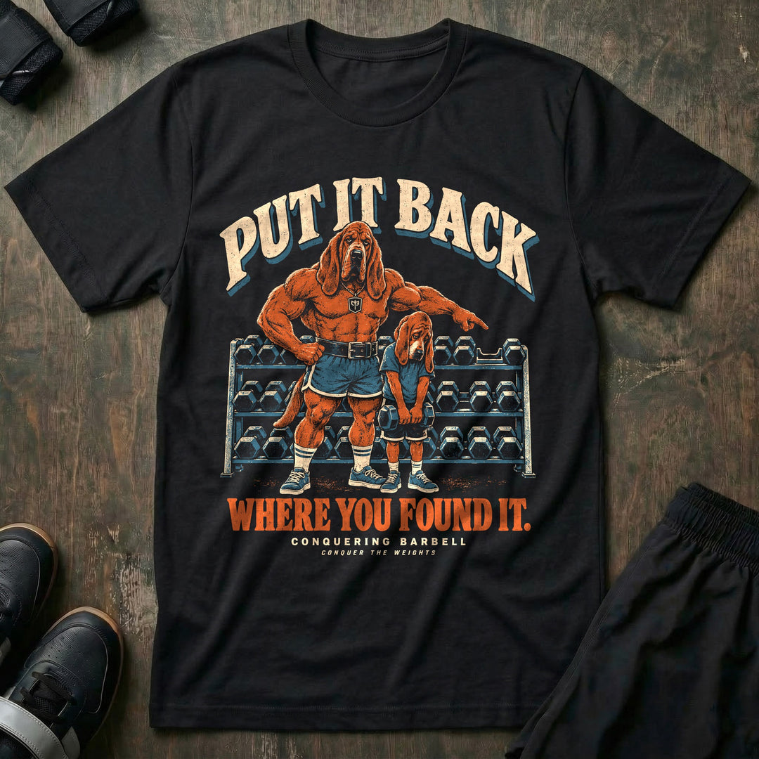 Put It Back Where You Found It - Tee front graphic in Black with a bloodhound dad pointing at a dumbbell rack while a young bloodhound holds a dumbbell with his head down - Conquering Barbell