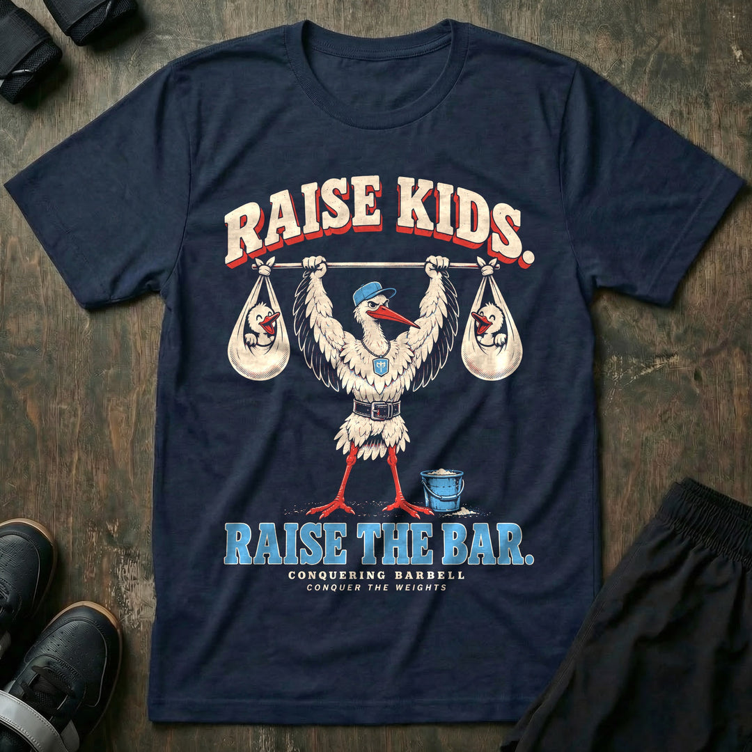 Raise Kids. Raise the Bar - Tee front graphic in Navy with a stork dad in a ball cap pressing a barbell overhead with a baby bundle hanging from each end - Conquering Barbell