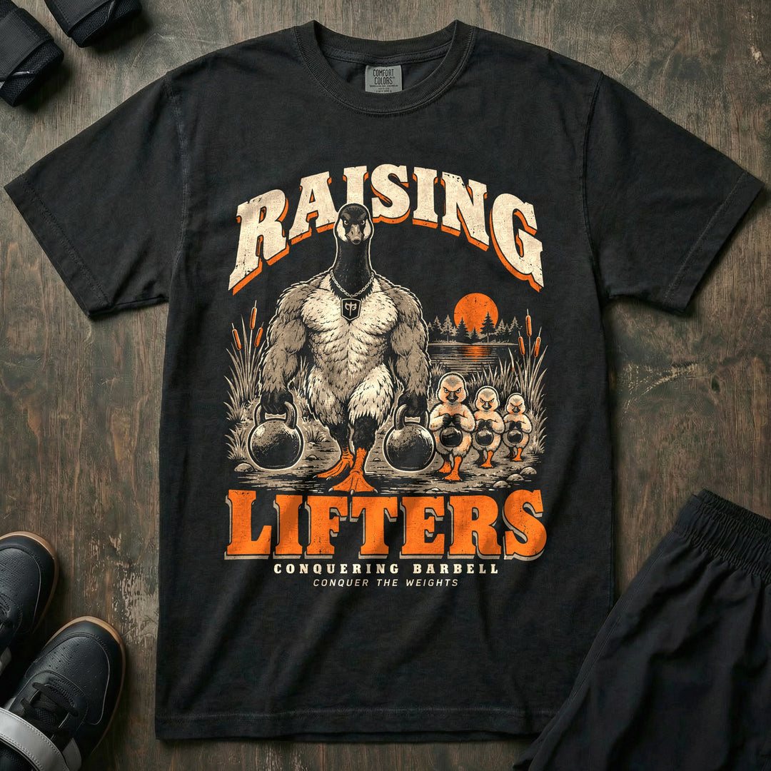 Raising Lifters - Relaxed Fit Tee front graphic in Black with a goose dad carrying two kettlebells along a marsh followed by three goslings carrying small kettlebells - Conquering Barbell