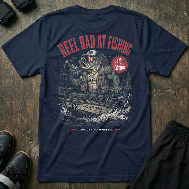 Reel Bad at Fishing tee in Navy: a jacked gator in a cap and vest cruising in a fishing boat with a dumbbell in hand