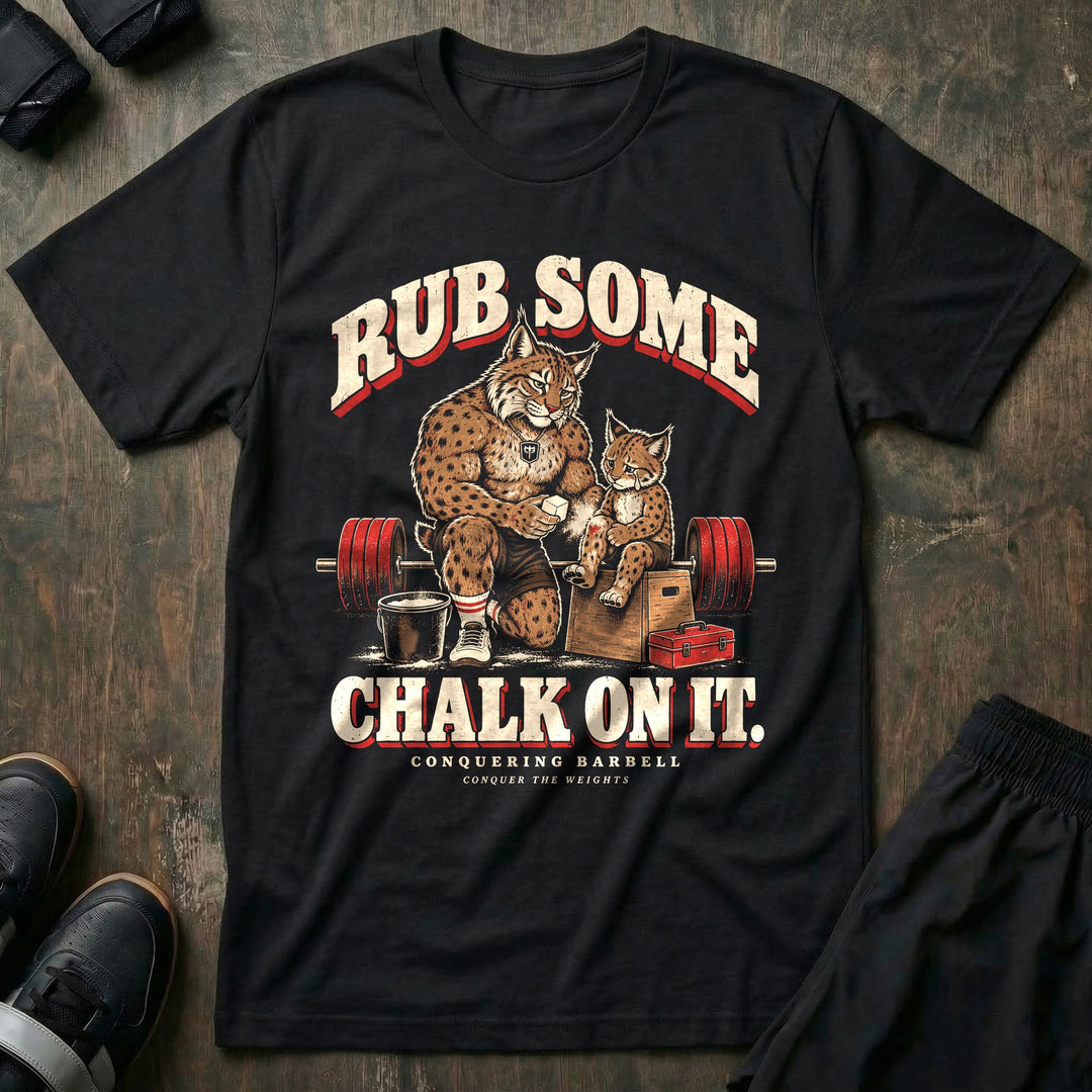 Rub Some Chalk on It - Tee front graphic in Black with a bobcat dad kneeling and rubbing chalk on the leg of a crying bobcat cub sitting on a wooden box - Conquering Barbell