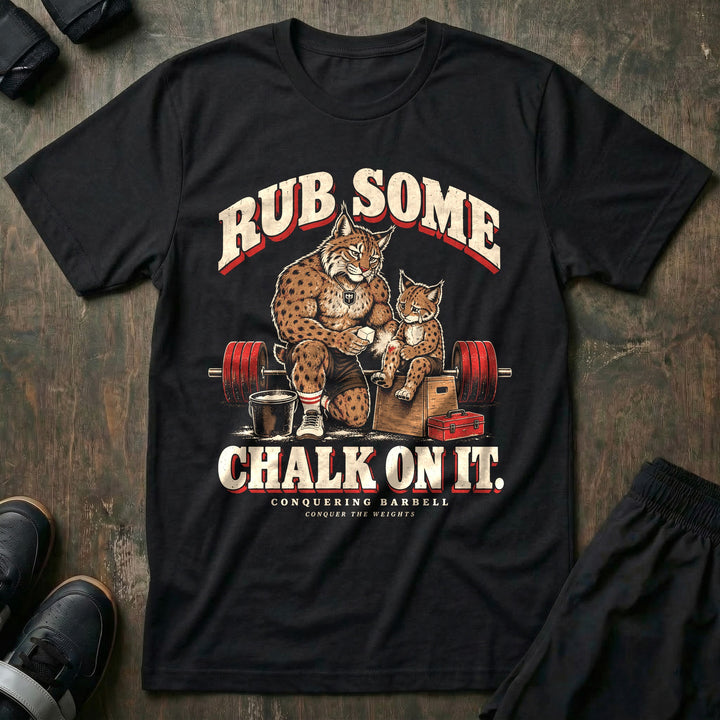 Rub Some Chalk on It - Tee front graphic in Black with a bobcat dad kneeling and rubbing chalk on the leg of a crying bobcat cub sitting on a wooden box - Conquering Barbell