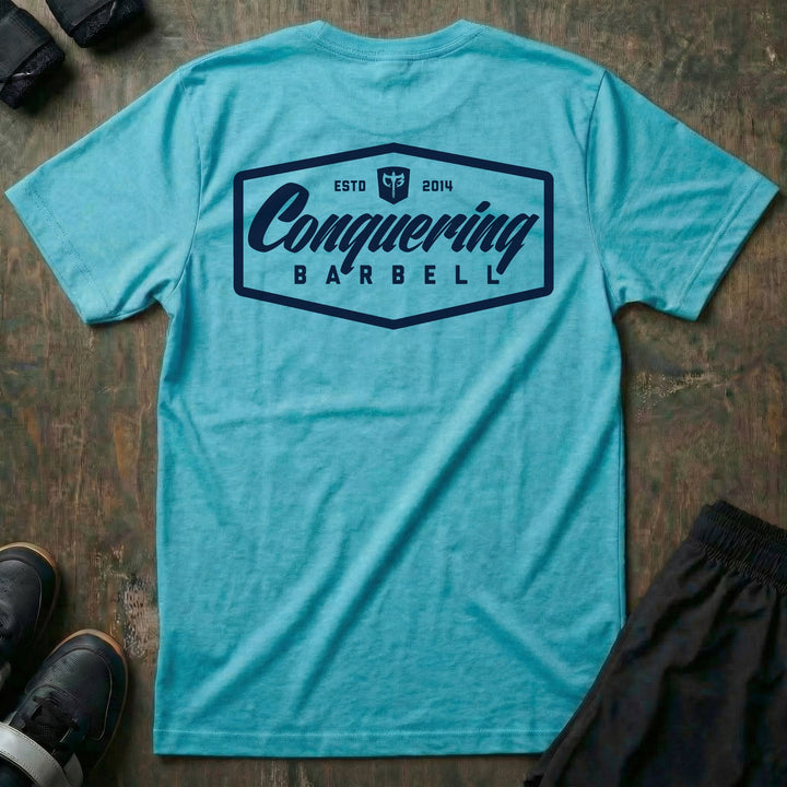 Script Logo Summer Vibes Edition tee in Tahiti: the classic Conquering Barbell script logo inside a bold badge frame
