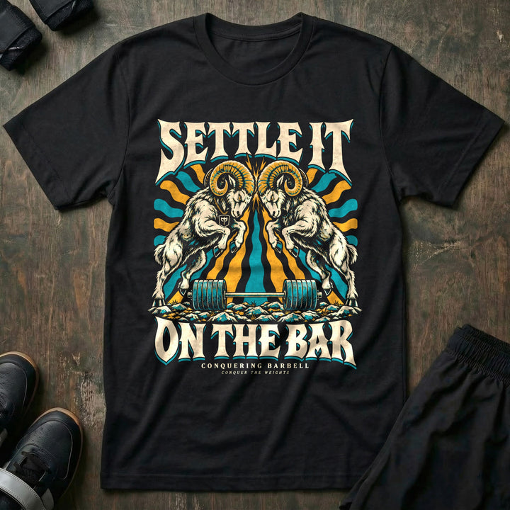Settle It on the Bar - Tee front graphic in Black with two bighorn rams locking horns over a loaded barbell - Conquering Barbell