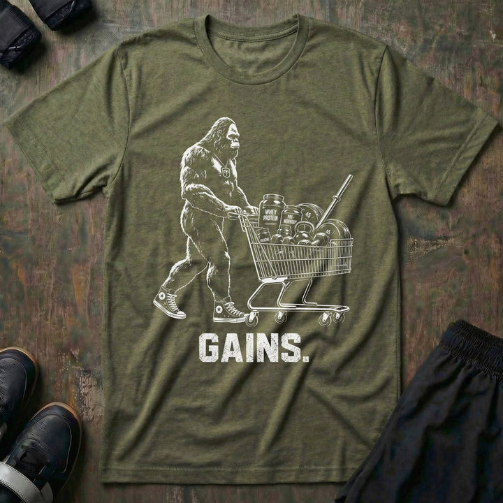 Shopping for Gains tee in Military: Bigfoot in high tops pushing a shopping cart loaded with protein