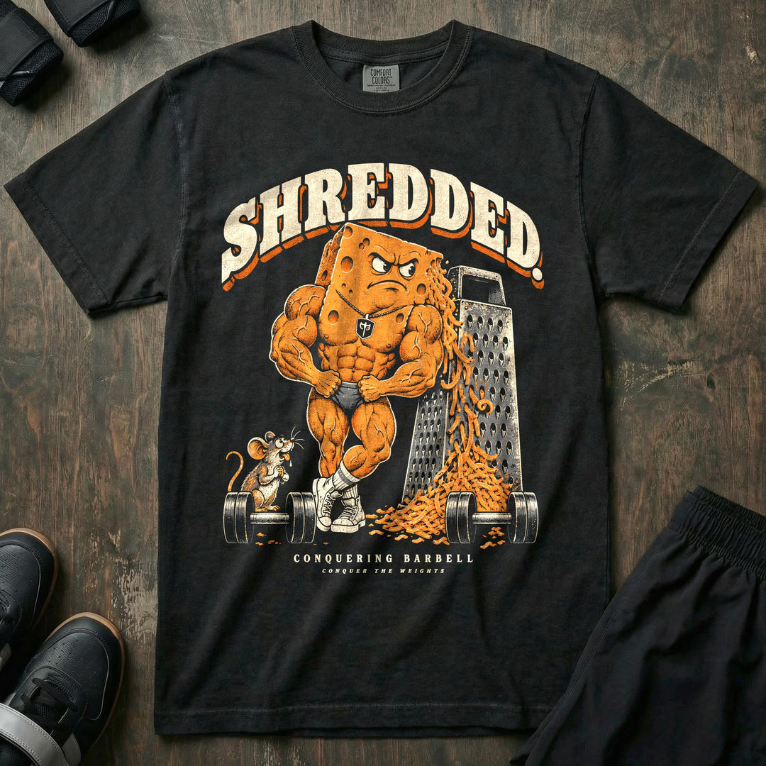 Shredded - Relaxed Fit Tee front graphic in Black with a muscular block of cheese posing beside a cheese grater and a pile of shreds - Conquering Barbell