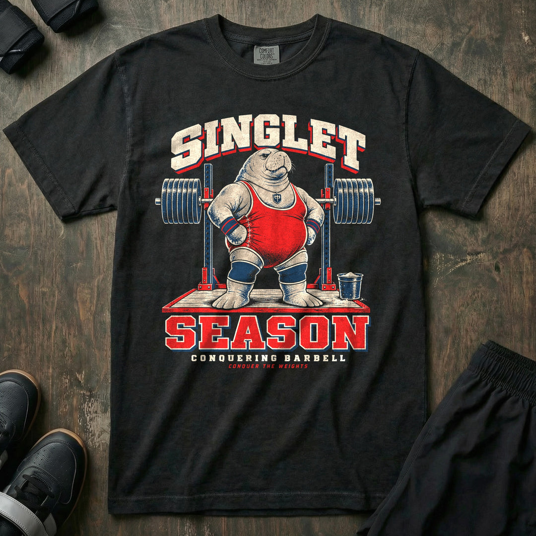 Singlet Season - Relaxed Fit Tee front graphic in Black with a manatee in a red singlet and knee sleeves standing on a lifting platform in front of a loaded rack - Conquering Barbell