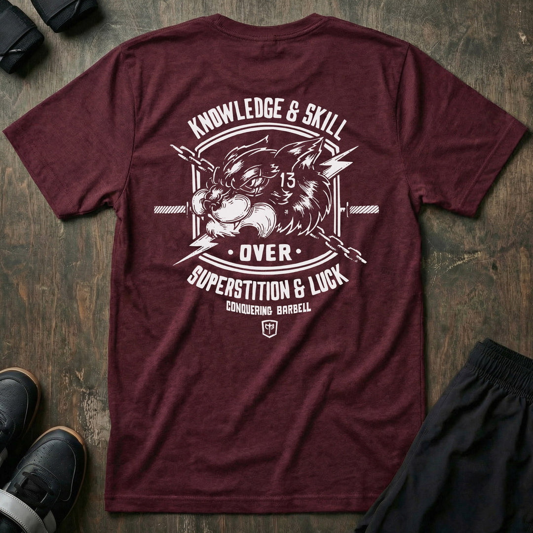 Skill Over Luck tee in Maroon: a snarling black cat marked with 13 flanked by crossed barbells and lightning bolts