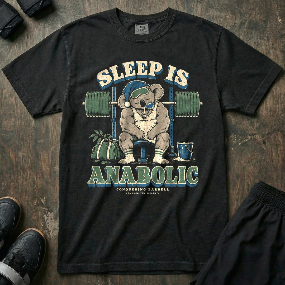 Sleep Is Anabolic - Relaxed Fit Tee front graphic in Black with a koala in a nightcap and eye mask asleep on a bench under a loaded barbell - Conquering Barbell
