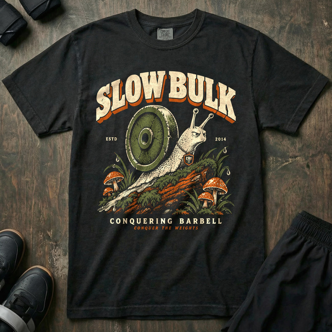 Slow Bulk - Relaxed Fit Tee front graphic in Black with a snail with a weight plate for a shell crossing a mossy log - Conquering Barbell