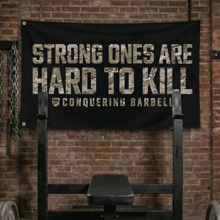 Strong Ones are Hard to Kill - Multi Camo - Polyester Flag, horizontal black gym flag with multi camo block letters STRONG ONES ARE HARD TO KILL - Conquering Barbell