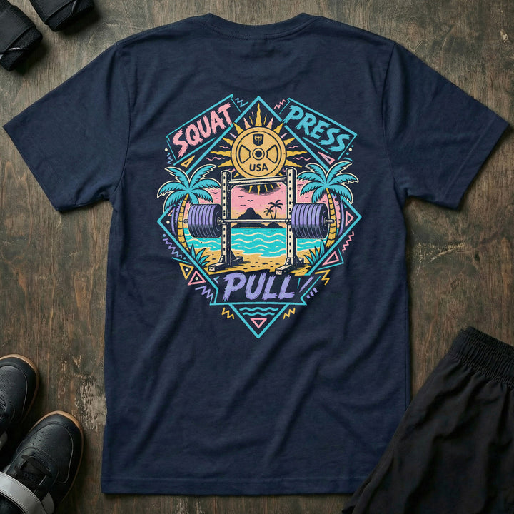 Sunset Iron tee in Navy: a loaded barbell rack on the sand with palm trees swaying under a pink sun