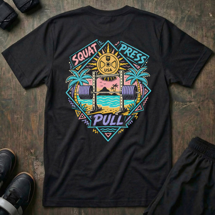 Sunset Iron tee in Black: a loaded barbell rack on the sand with palm trees swaying under a pink sun