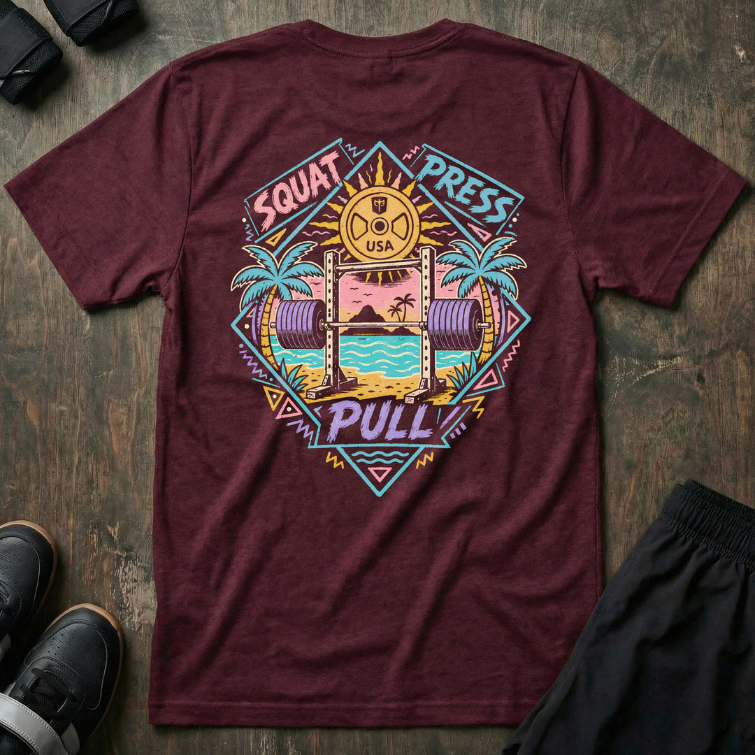 Sunset Iron tee in Maroon: a loaded barbell rack on the sand with palm trees swaying under a pink sun