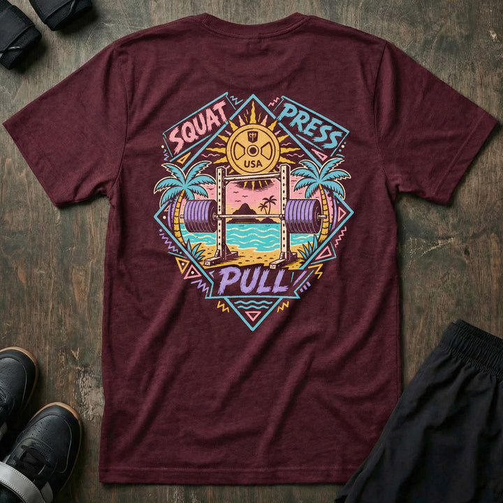 Sunset Iron tee in Maroon: a loaded barbell rack on the sand with palm trees swaying under a pink sun