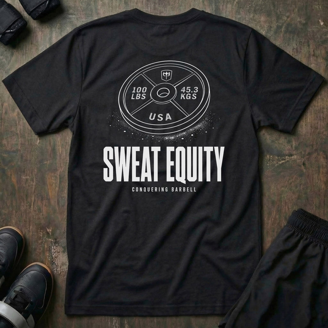 Sweat Equity tee in Black: a 100 lb USA plate with the CB shield and chalk dust scattered at its base
