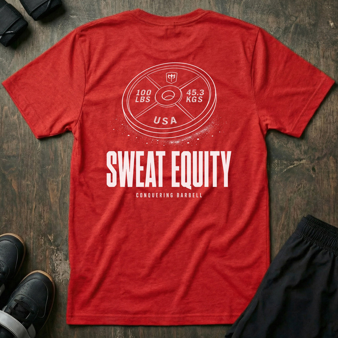 Sweat Equity tee in Red: a 100 lb USA plate with the CB shield and chalk dust scattered at its base