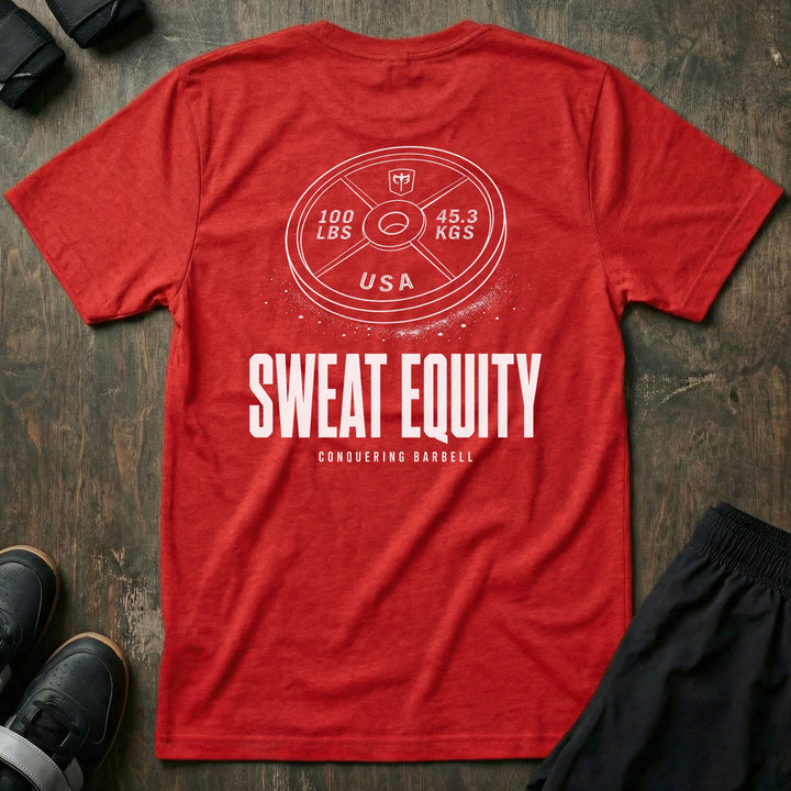 Sweat Equity tee in Red: a 100 lb USA plate with the CB shield and chalk dust scattered at its base