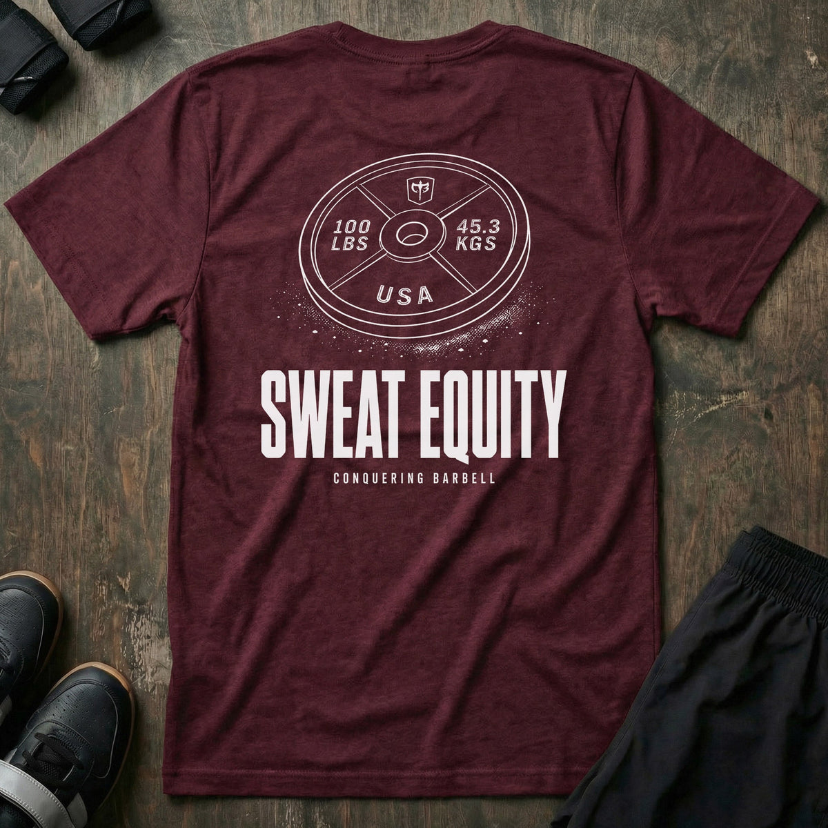 Sweat Equity tee in Maroon: a 100 lb USA plate with the CB shield and chalk dust scattered at its base