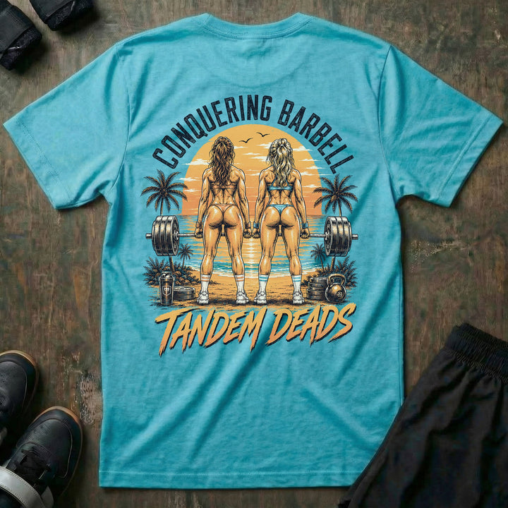 Tandem Deads tee in Tahiti: two athletic women deadlifting side by side on a palm-lined beach at sunset