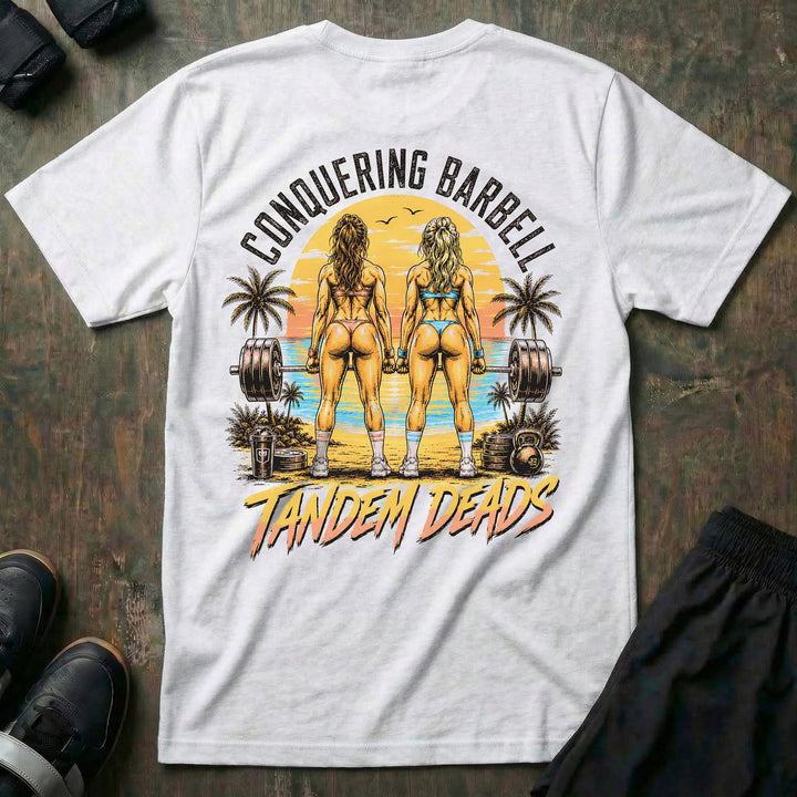 Tandem Deads tee in White: two athletic women deadlifting side by side on a palm-lined beach at sunset