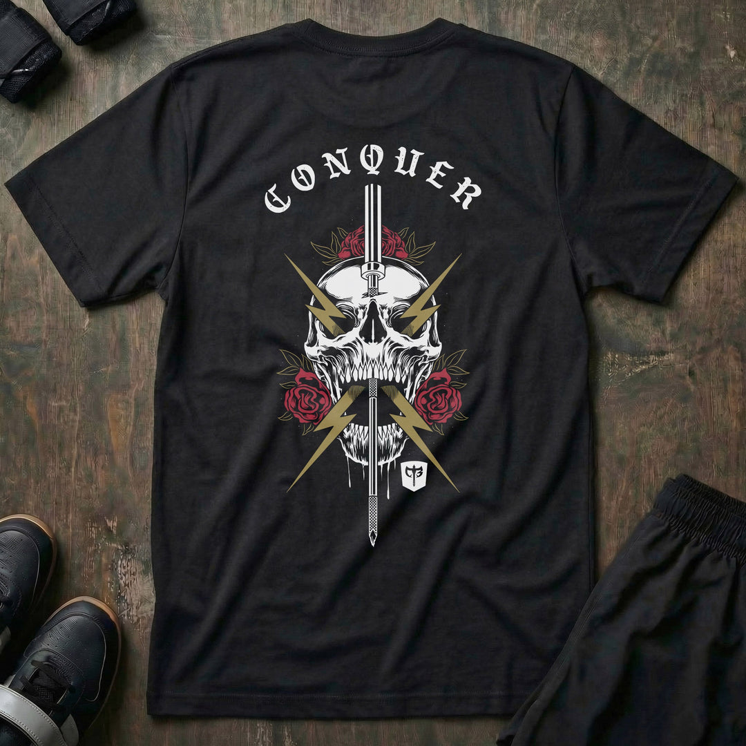 The Conqueror tee in Black: a skull crowned in red roses and run through by a sword crackling with gold lightning