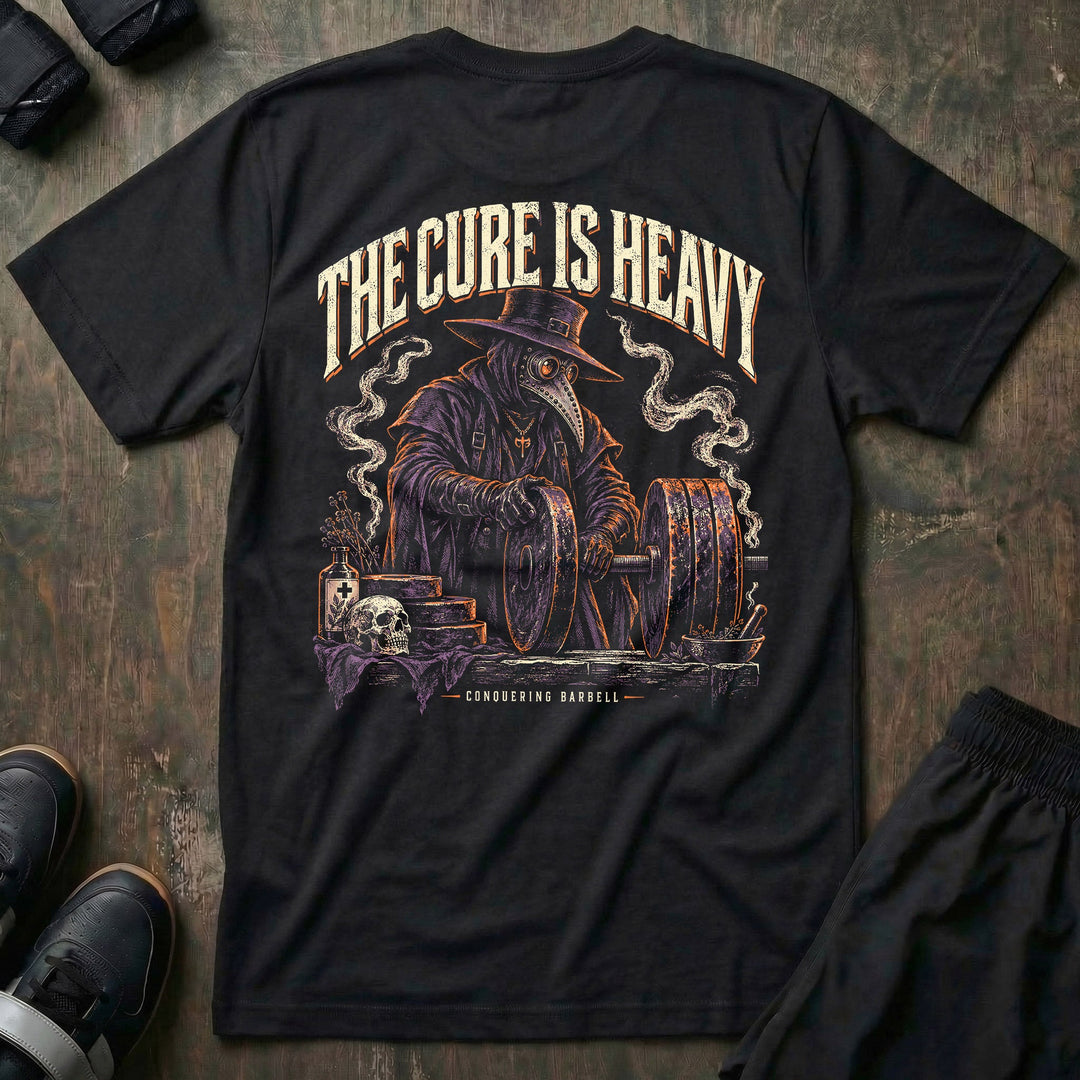 The Cure is Heavy tee in Black: a plague doctor working over a loaded barbell like a grim physician at the operating table