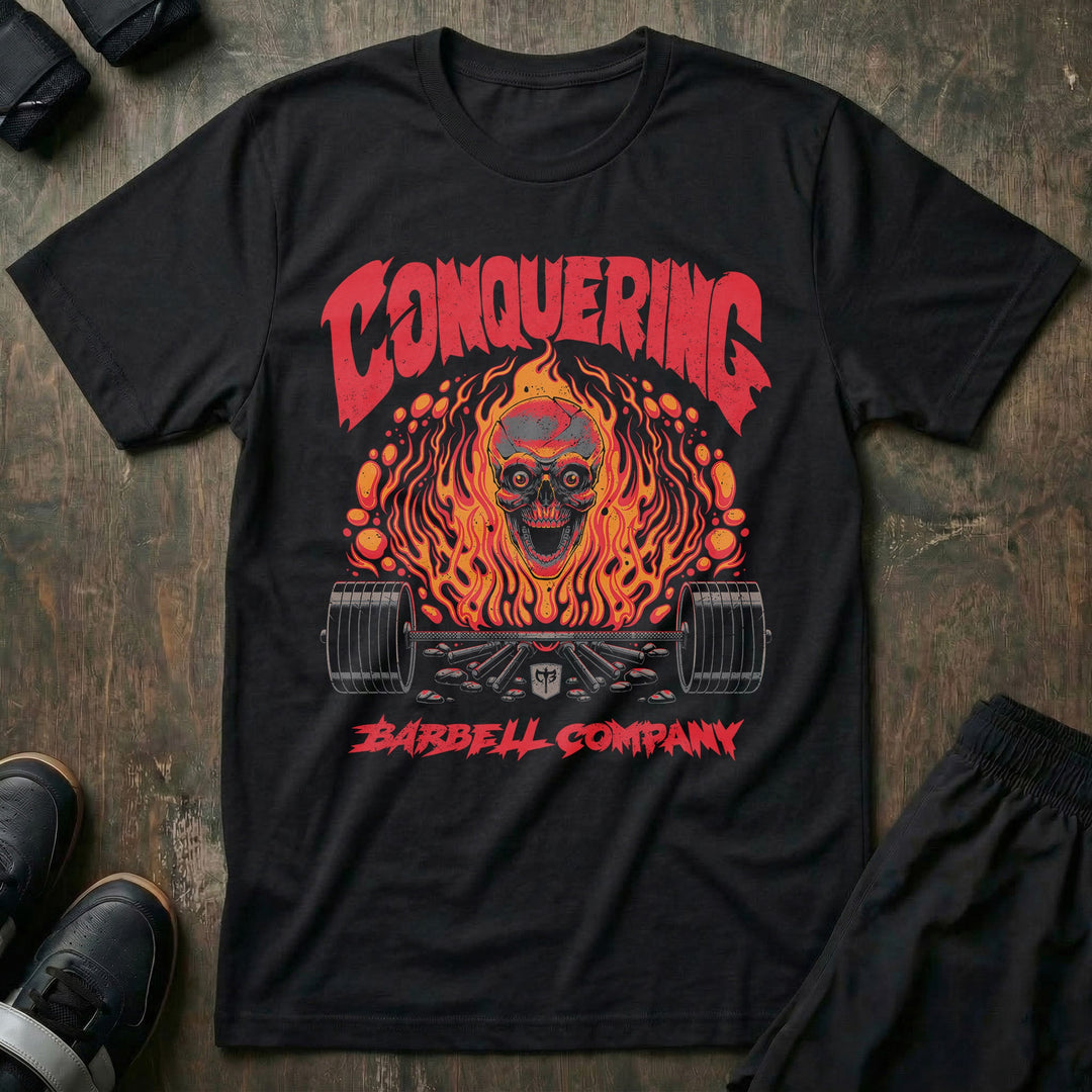 The Flaming Skull tee in Black: a skull engulfed in orange flame over a loaded barbell