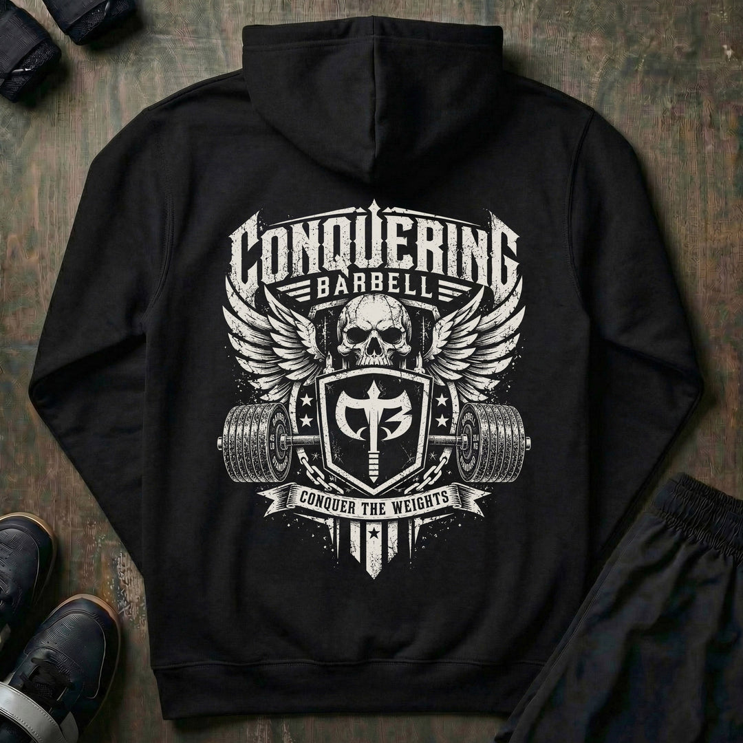The Standard pullover hoodie in Black: a winged skull rising behind the Conquering Barbell shield