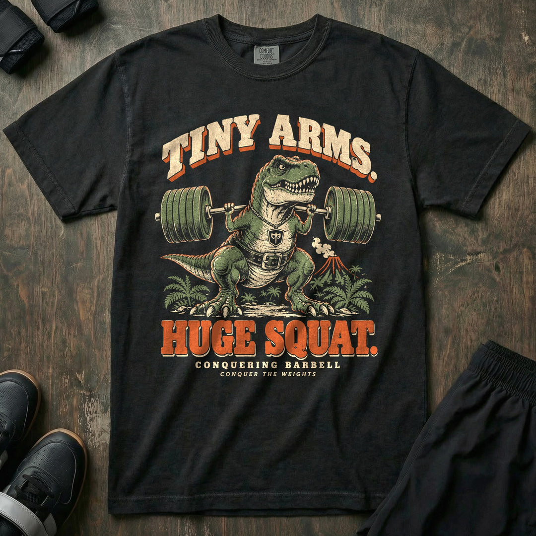 Tiny Arms Huge Squat - Relaxed Fit Tee front graphic in Black with a T. rex in a lifting belt squatting a loaded barbell with tiny arms - Conquering Barbell