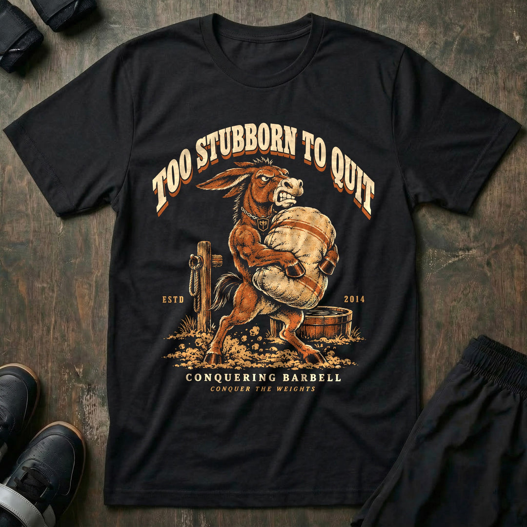 Too Stubborn to Quit - Tee front graphic in Black with a mule with teeth bared carrying a heavy sandbag - Conquering Barbell