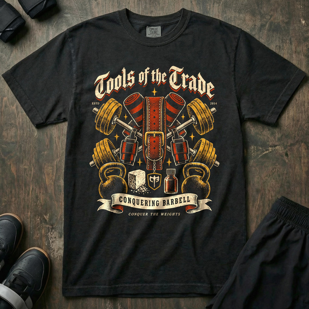 Tools of the Trade - Relaxed Fit Tee front graphic in Black with crossed barbells with a lifting belt, knee wraps, chalk, and kettlebells - Conquering Barbell