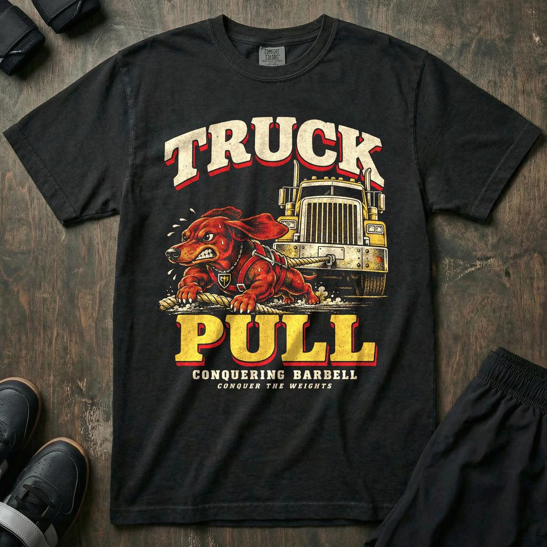 Truck Pull - Relaxed Fit Tee front graphic in Black with a dachshund in a harness pulling a semi truck with a rope - Conquering Barbell