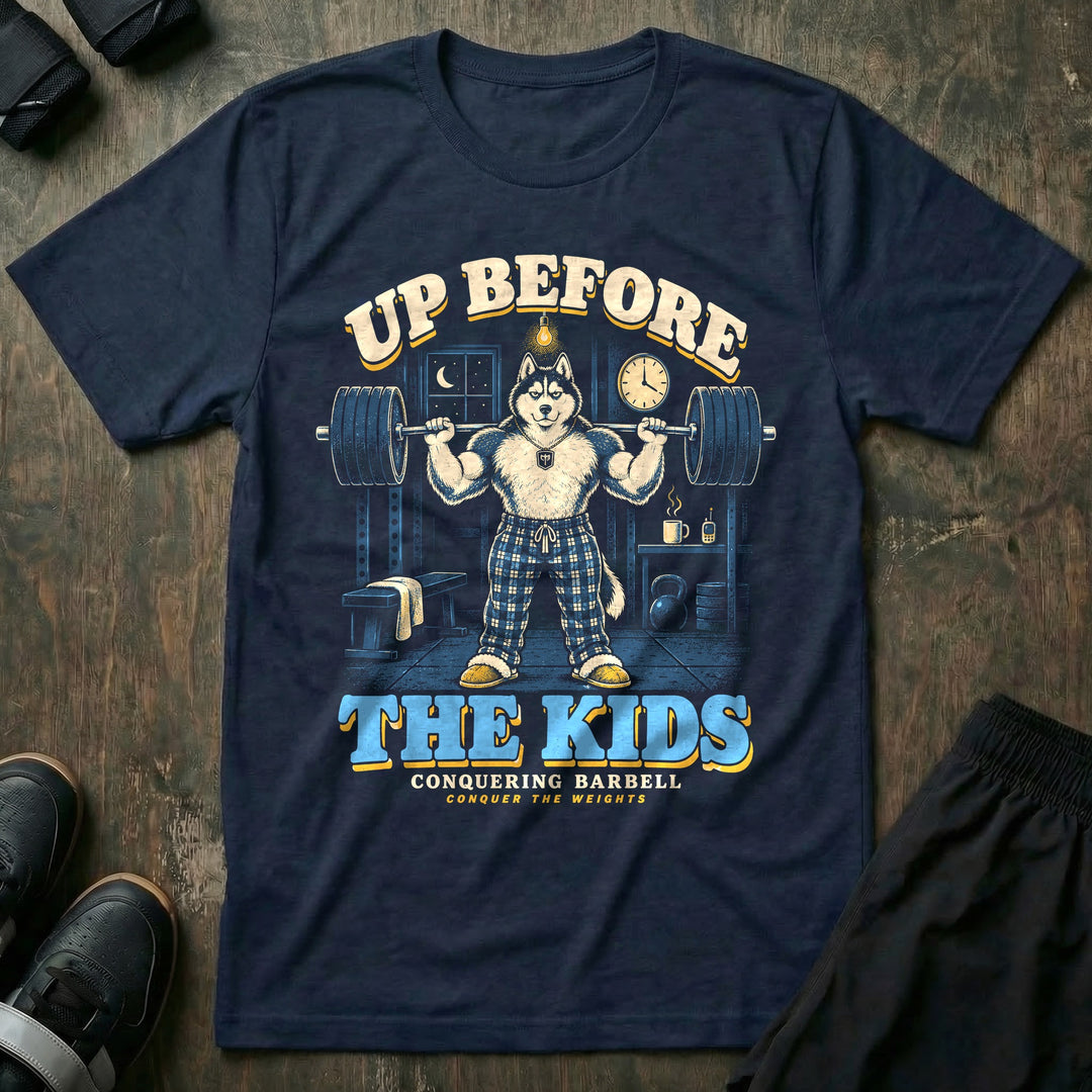 Up Before the Kids - Tee front graphic in Navy with a husky dad in plaid pajama pants squatting a loaded barbell in a garage gym at night with a coffee mug and baby monitor on a shelf - Conquering Barbell