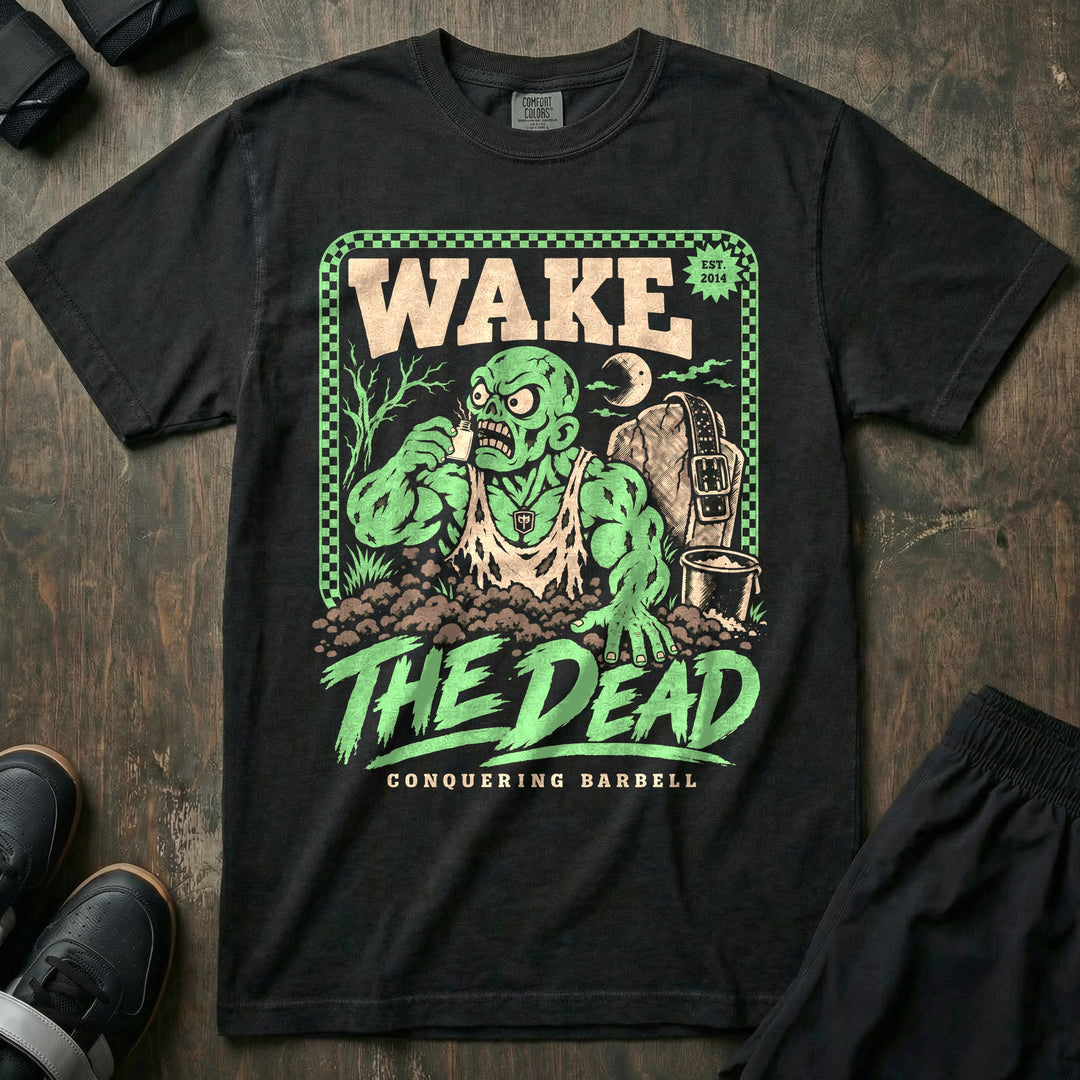 Wake the Dead V2 - Relaxed Fit Tee front graphic in Black with a zombie lifter climbing out of a grave sniffing smelling salts beside a tombstone with a lifting belt hung on it - Conquering Barbell