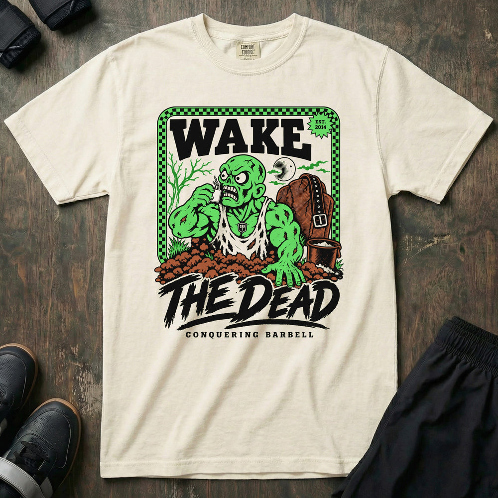 Wake the Dead V2 - Relaxed Fit Tee front graphic in Ivory with a zombie lifter climbing out of a grave sniffing smelling salts beside a tombstone with a lifting belt hung on it - Conquering Barbell