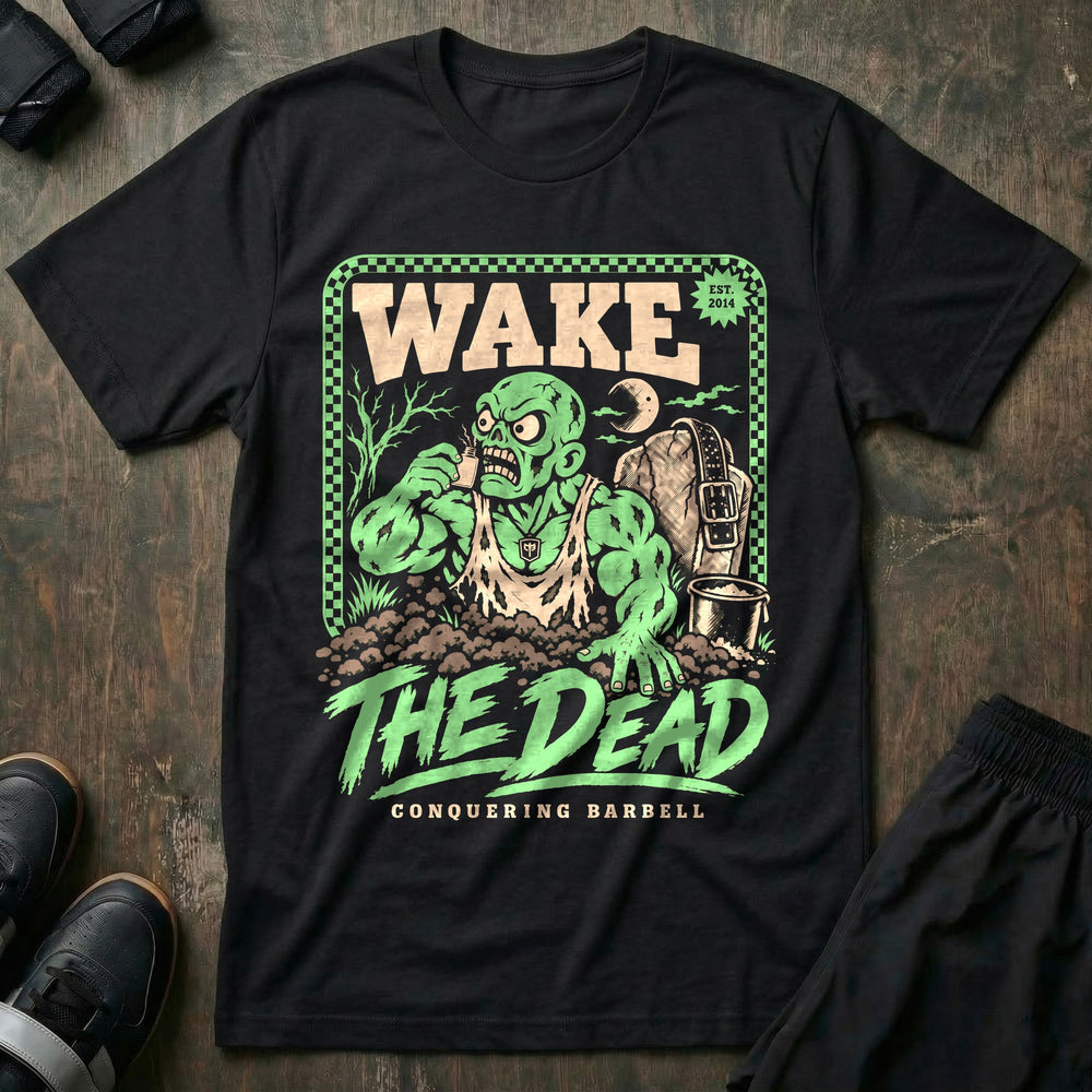 Wake the Dead V2 - Tee front graphic in Black with a zombie lifter climbing out of a grave sniffing smelling salts beside a tombstone with a lifting belt hung on it - Conquering Barbell