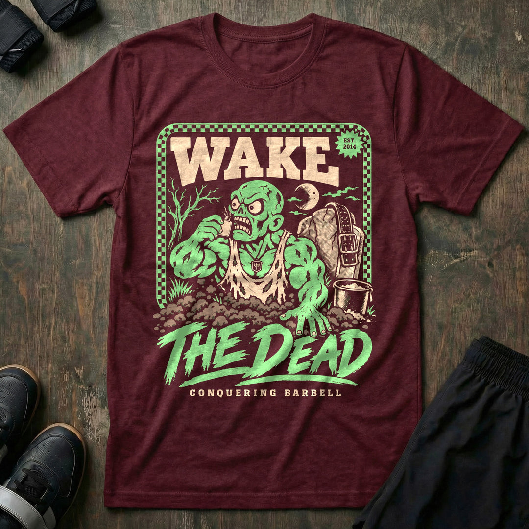 Wake the Dead V2 - Tee front graphic in Maroon with a zombie lifter climbing out of a grave sniffing smelling salts beside a tombstone with a lifting belt hung on it - Conquering Barbell
