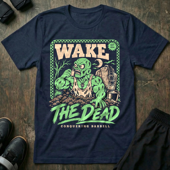 Wake the Dead V2 - Tee front graphic in Navy with a zombie lifter climbing out of a grave sniffing smelling salts beside a tombstone with a lifting belt hung on it - Conquering Barbell