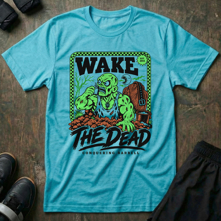 Wake the Dead V2 - Tee front graphic in Tahiti with a zombie lifter climbing out of a grave sniffing smelling salts beside a tombstone with a lifting belt hung on it - Conquering Barbell