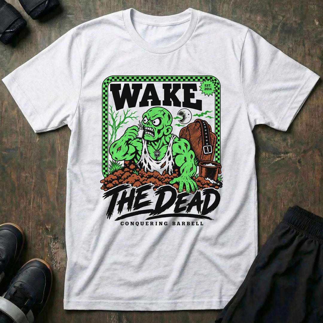Wake the Dead V2 - Tee front graphic in White with a zombie lifter climbing out of a grave sniffing smelling salts beside a tombstone with a lifting belt hung on it - Conquering Barbell