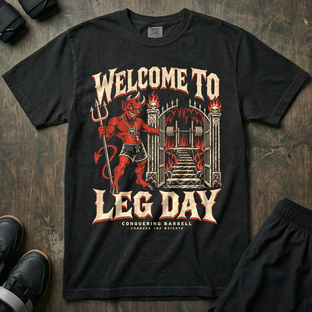 Welcome to Leg Day - Relaxed Fit Tee front graphic in Black with a grinning red devil holding open fiery gates that lead to a squat rack - Conquering Barbell