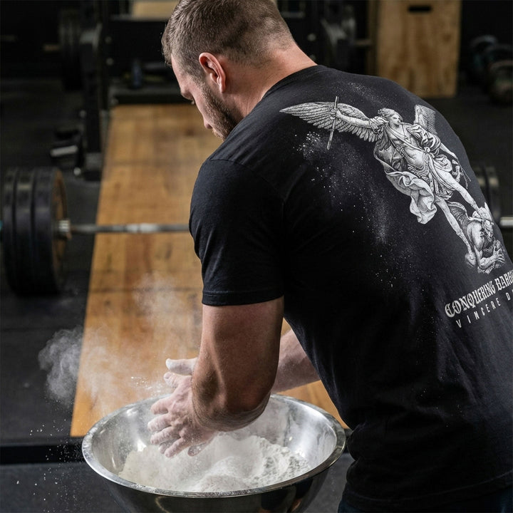 Win the Day Angel vs Dem tee in Black: a winged guardian driving his weapon down on a demon in a classic engraving style
