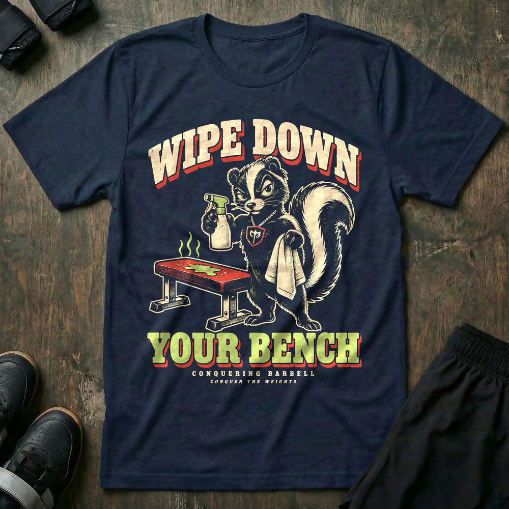 Wipe Down Your Bench - Tee front graphic in Navy with a skunk with a spray bottle and towel glaring at a sweaty bench - Conquering Barbell