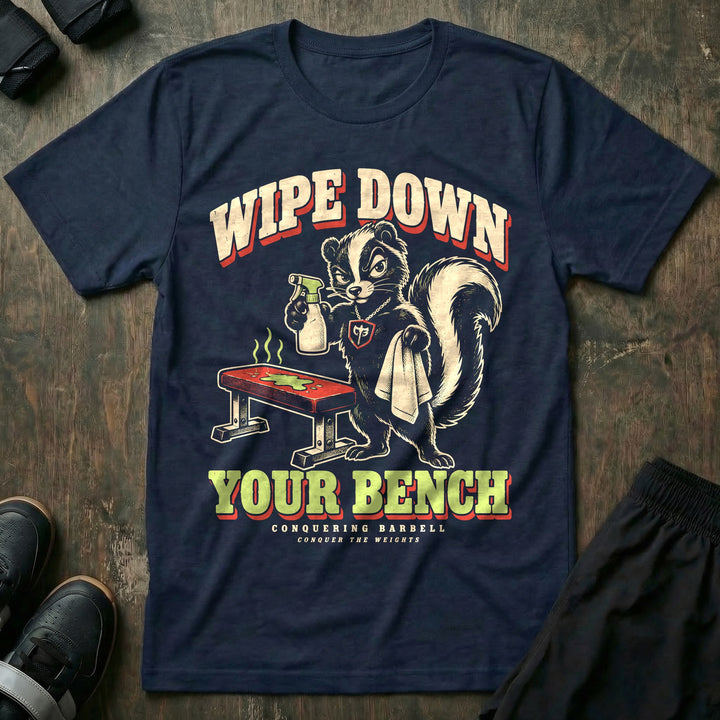 Wipe Down Your Bench - Tee front graphic in Navy with a skunk with a spray bottle and towel glaring at a sweaty bench - Conquering Barbell