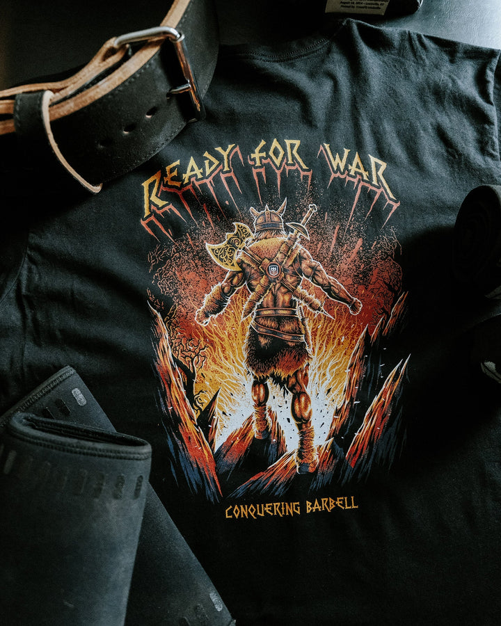 Ready for War tee in Black: an armored Viking warrior in full battle gear striding out of a wall of fire in orange and gold