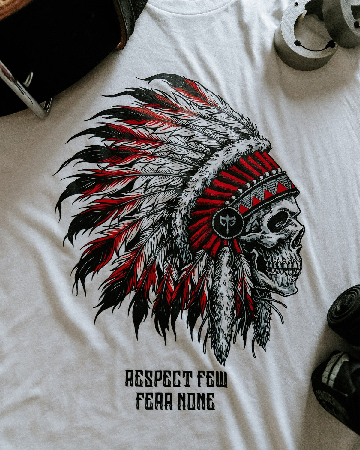 Respect Few, Fear None tee in White: a skull in a red and black feathered war bonnet