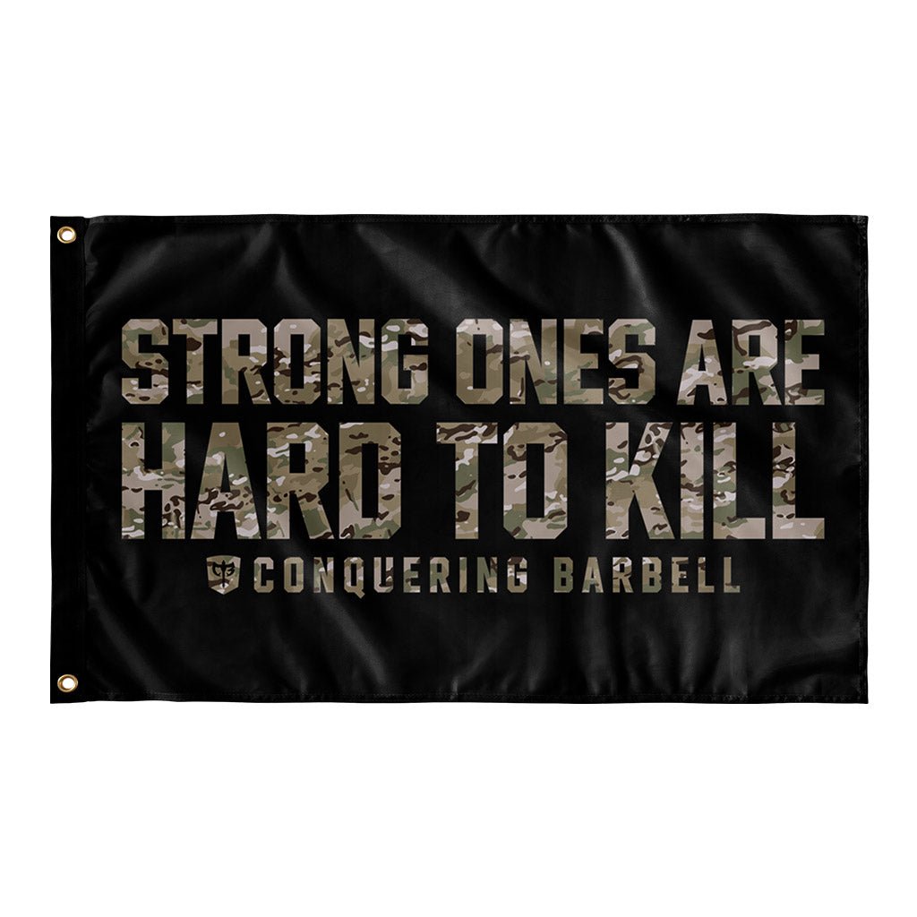 Strong Ones are Hard to Kill - Multi Camo - Polyester Flag, horizontal gym flag hanging in a home gym - Conquering Barbell